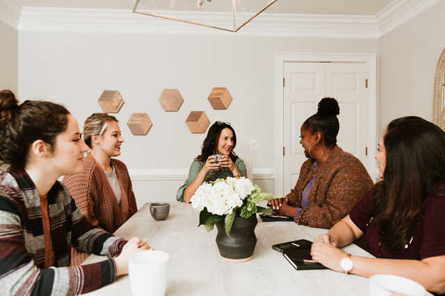 Womens Group Sitting Around Kitchen Table Talking