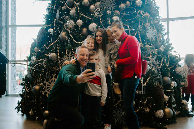 family taking a picture in front of the christmas tree in the lobby